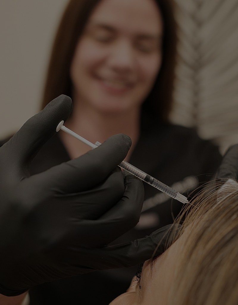 Cosmetic procedure with syringe and gloved hand.