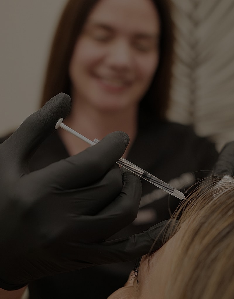 Cosmetic procedure with syringe and gloved hand.